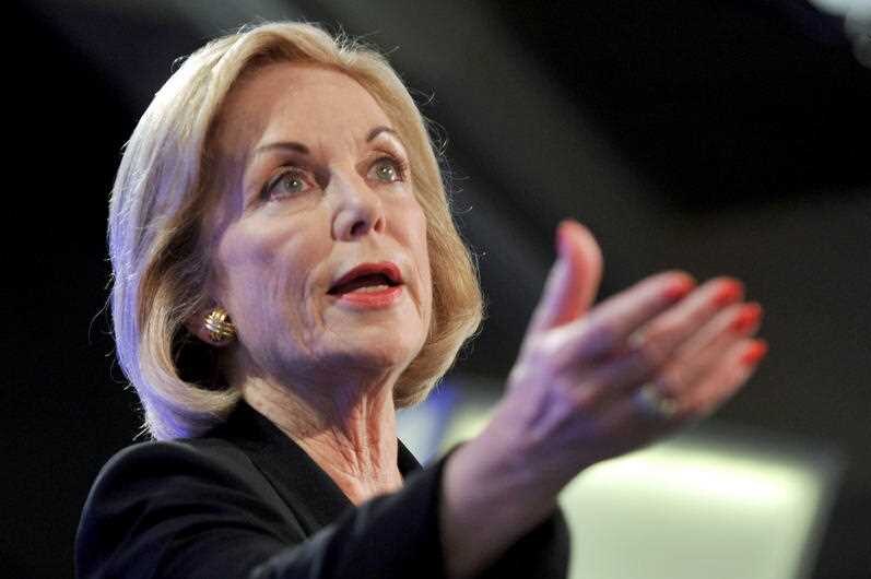 Close up portrait of Ita Buttrose looking to her left and gesturing with her manicured right hand