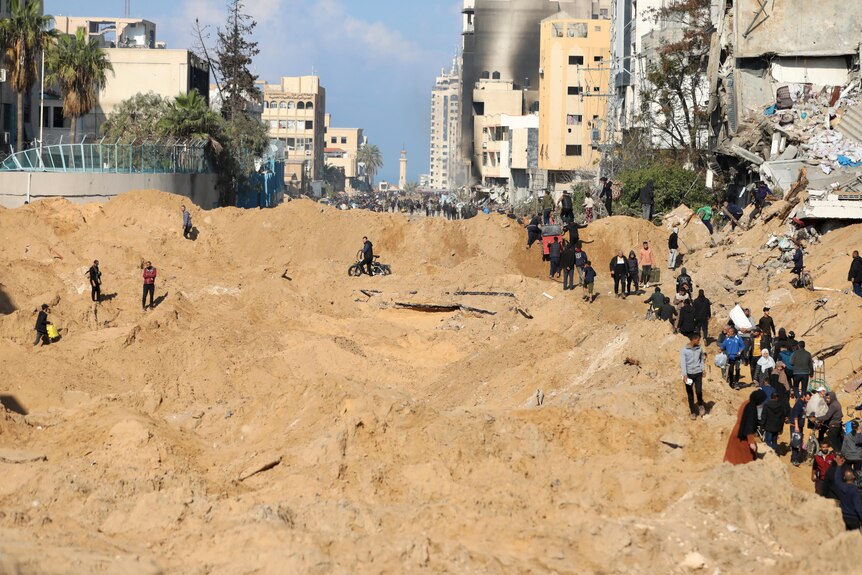 Rows of Palestinians walk through uneven dirt