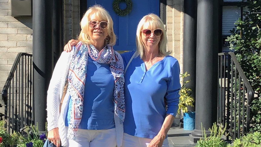 Hazel and Suzanne standing out the front of a house with a blue door.