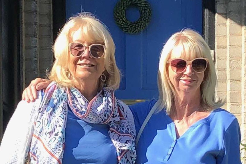 Hazel and Suzanne standing out the front of a house with a blue door.