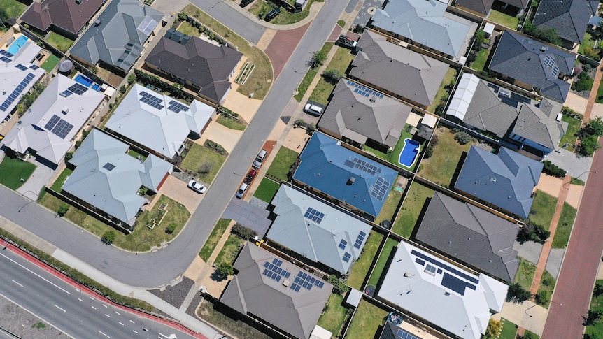 An aerial shot of a residential area. Many of the roofs have solar panels installed.