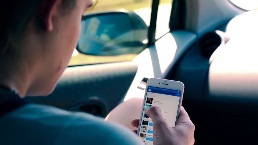 A woman holds her mobile phone while sitting in a car.