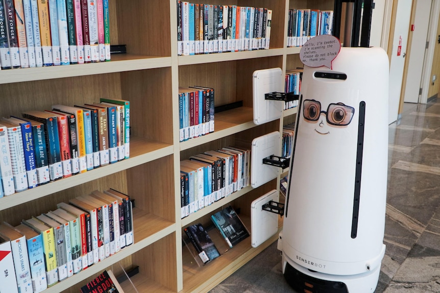 A robot in a library scans barcodes on books. 