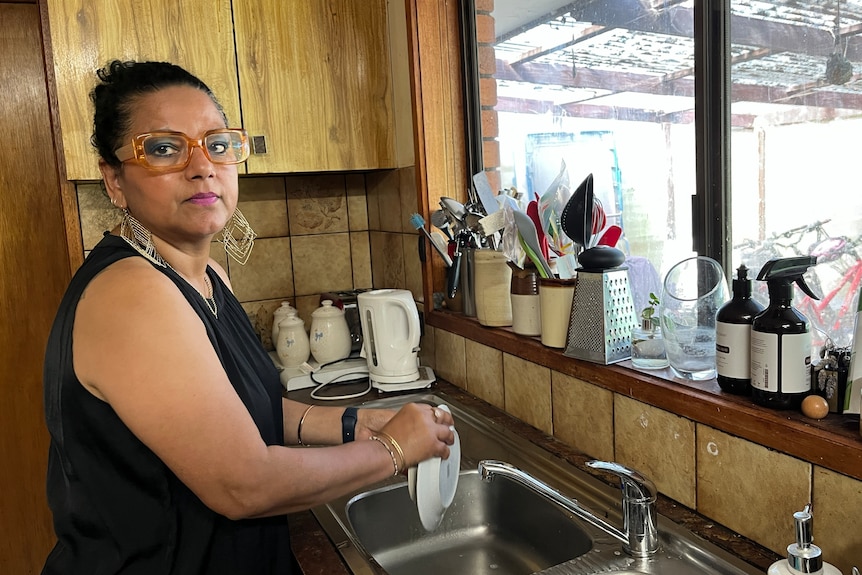 A woman washes dishes in a sink