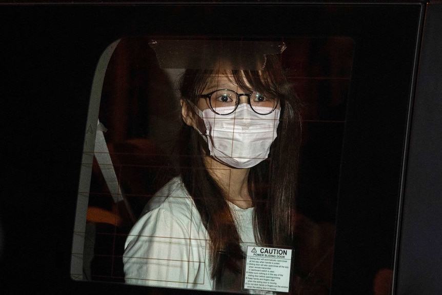 Agnes Chow wears a face mask as she looks out of a car window during her arrest in Hong Kong