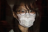 Agnes Chow wears a face mask as she looks out of a car window during her arrest in Hong Kong