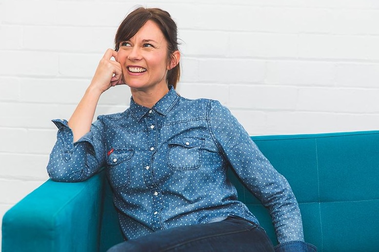 Smiling dark-haired woman on blue sofa