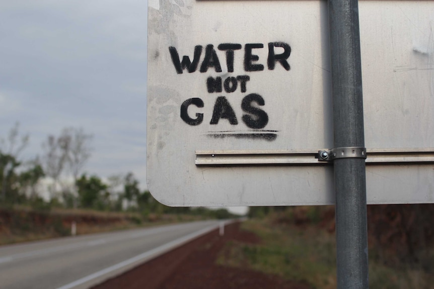 Grafitti reading 'water not gas' on a roadsign.