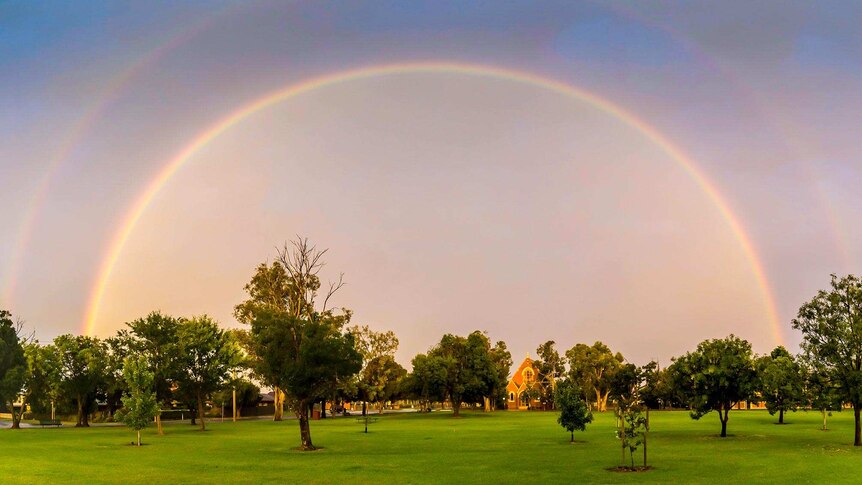 Photo taken in a lush, green park of a double rainbow formed over the town of Yarrawonga.