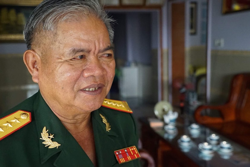 A Vietnamese war veteran wears a uniform outside his home.