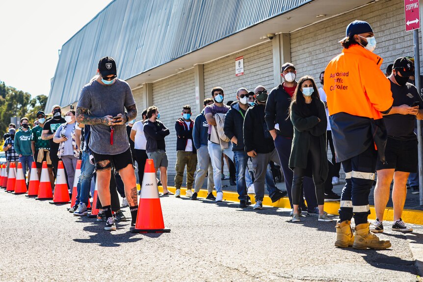 People wearing masks stand in line at a testing centre