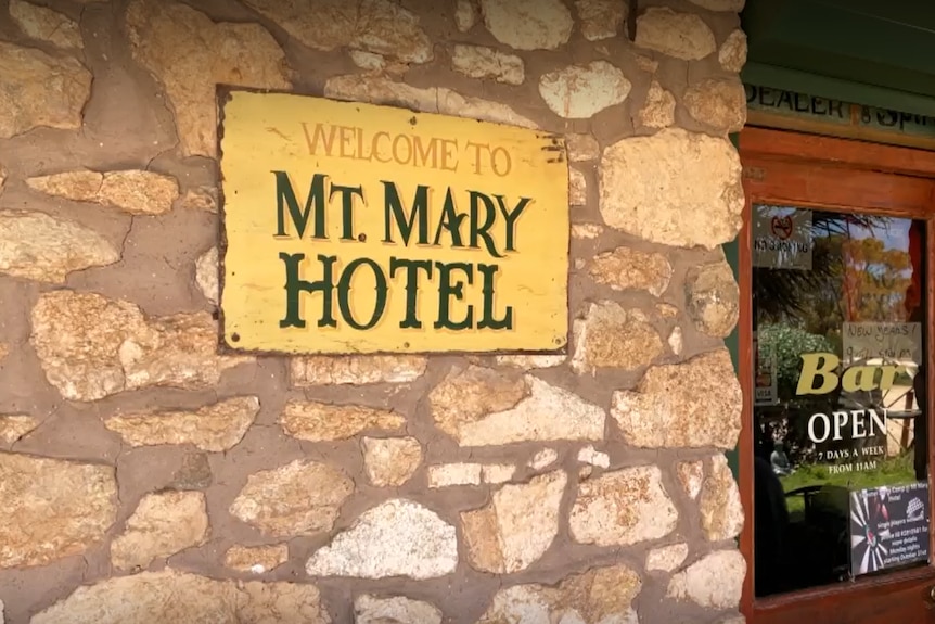 A sign on a stone wall saying welcome to Mt. Mary Hotel and a door