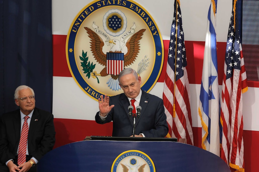 Israeli Prime Minister Benjamin Netanyahu gestures at a podium.