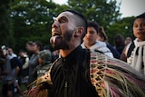 A Maori community leader with wide eyes sticks his tongue out as he performs haka.