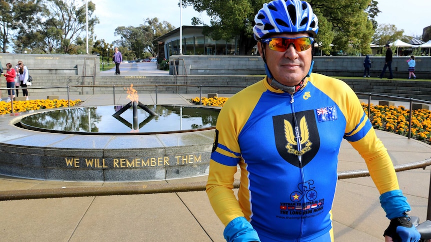 Vietnam veteran 'Truck' Sams dressed in cycling gear in front of the eternal flame in Kings Park.