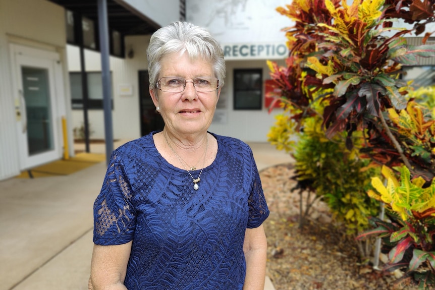 Vicki O'Donnell wears a blue shirt and stands next to a plant outside