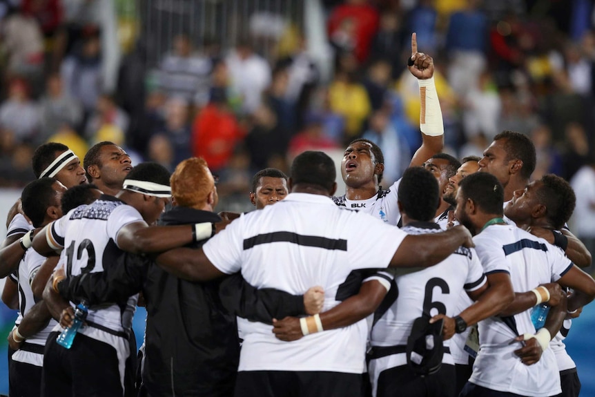 The Fijian rugby sevens team huddles after winning gold