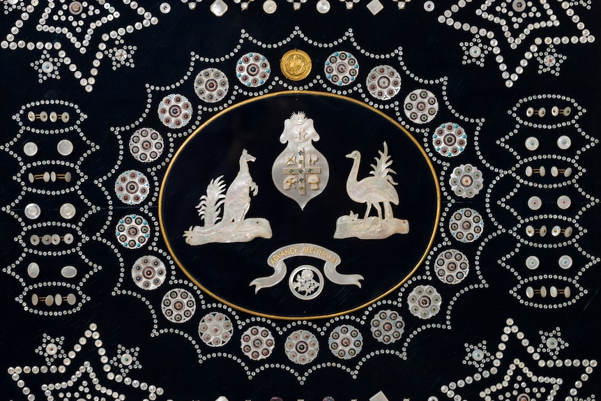 Buttons and shells arranged as kangaroo and emus on black material.