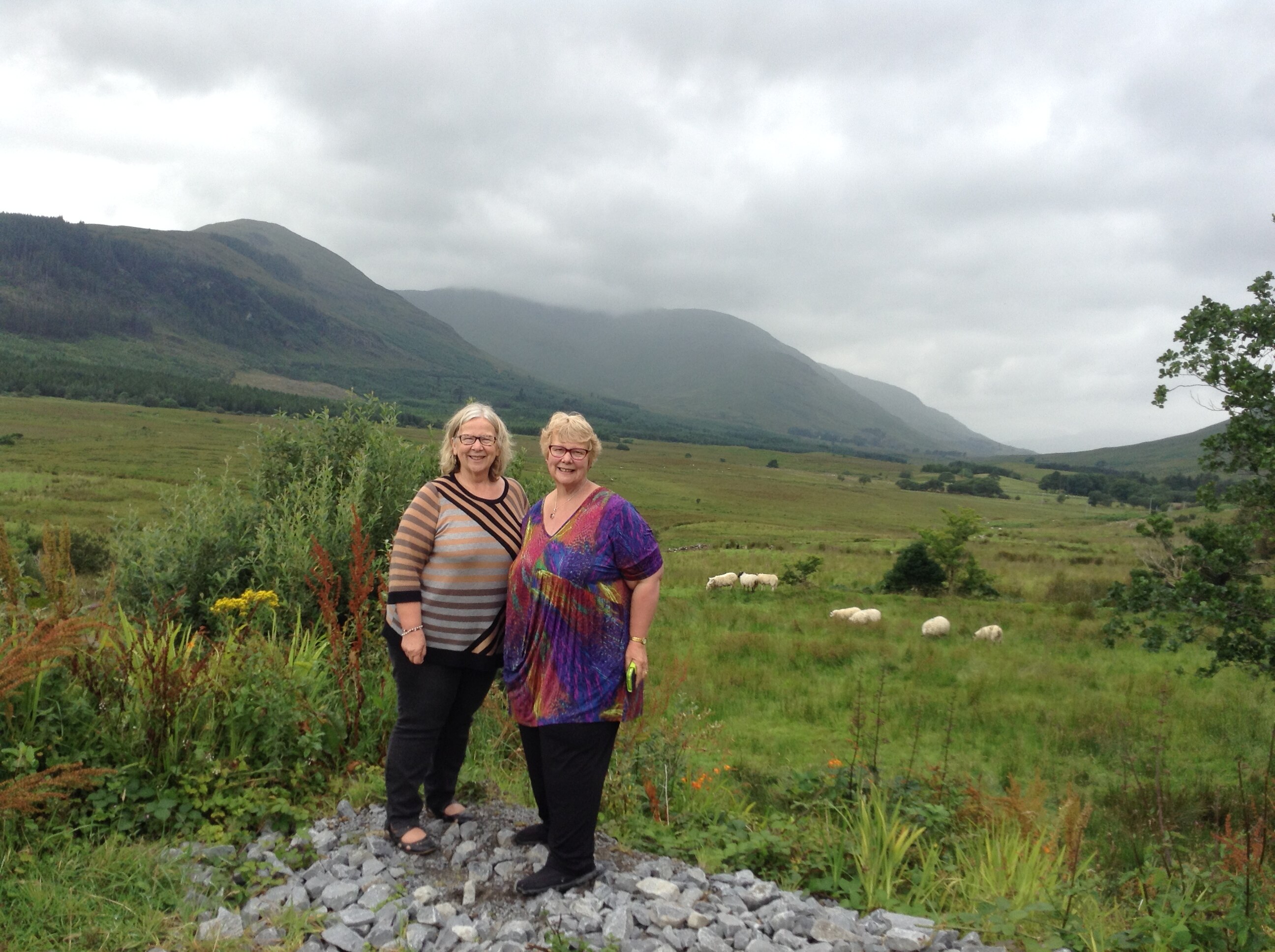Two women standing in a paddock with beautiful Irish mountains behind them