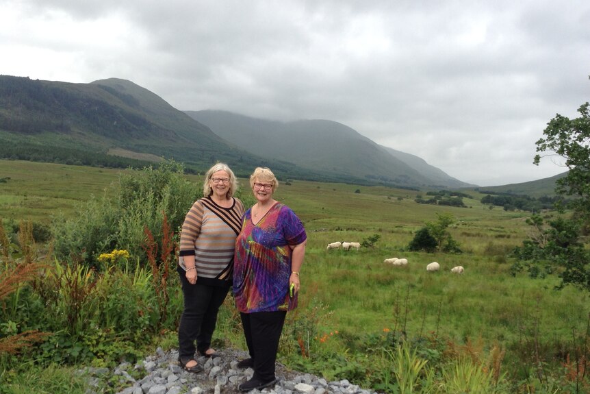 Two women standing in a paddock with beautiful Irish mountains behind them