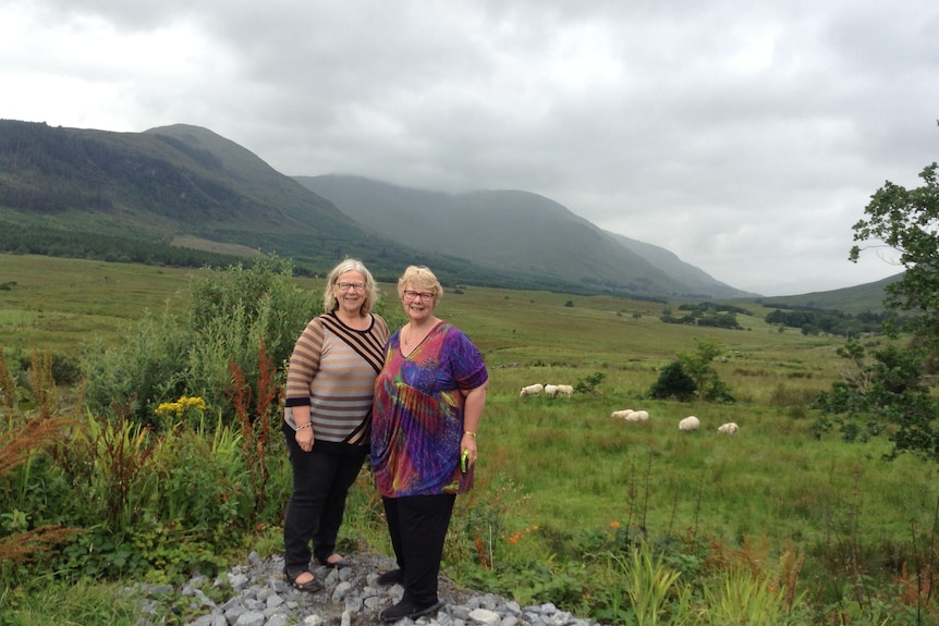 Two women standing in a paddock with beautiful Irish mountains behind them