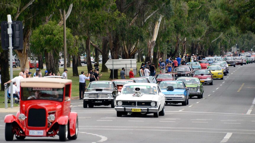 A parade of cars make their way down Northbourne Avenue as part of the 2014 Summernats city cruise.