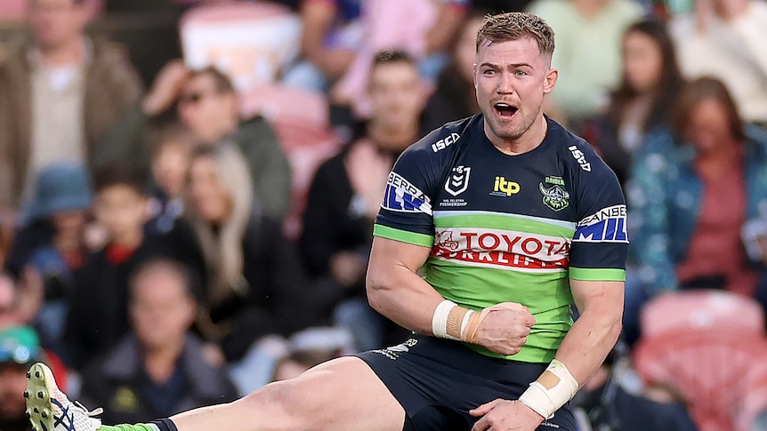 Canberra Raiders' Hudson Young jumps in the air and clenches his fist to celebrate an NRL try against the Newcastle Knights.