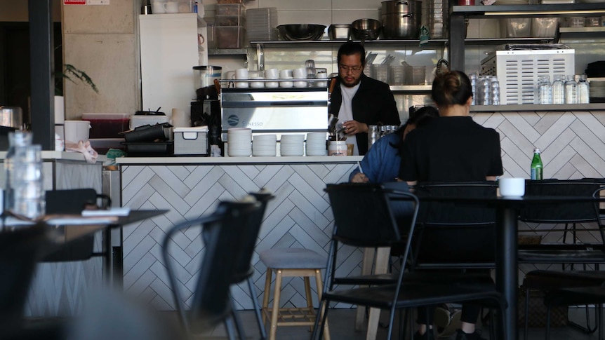 A man pouring a coffee behind a desk in a cafe