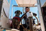 dog with life jacket and man with beard on boat 