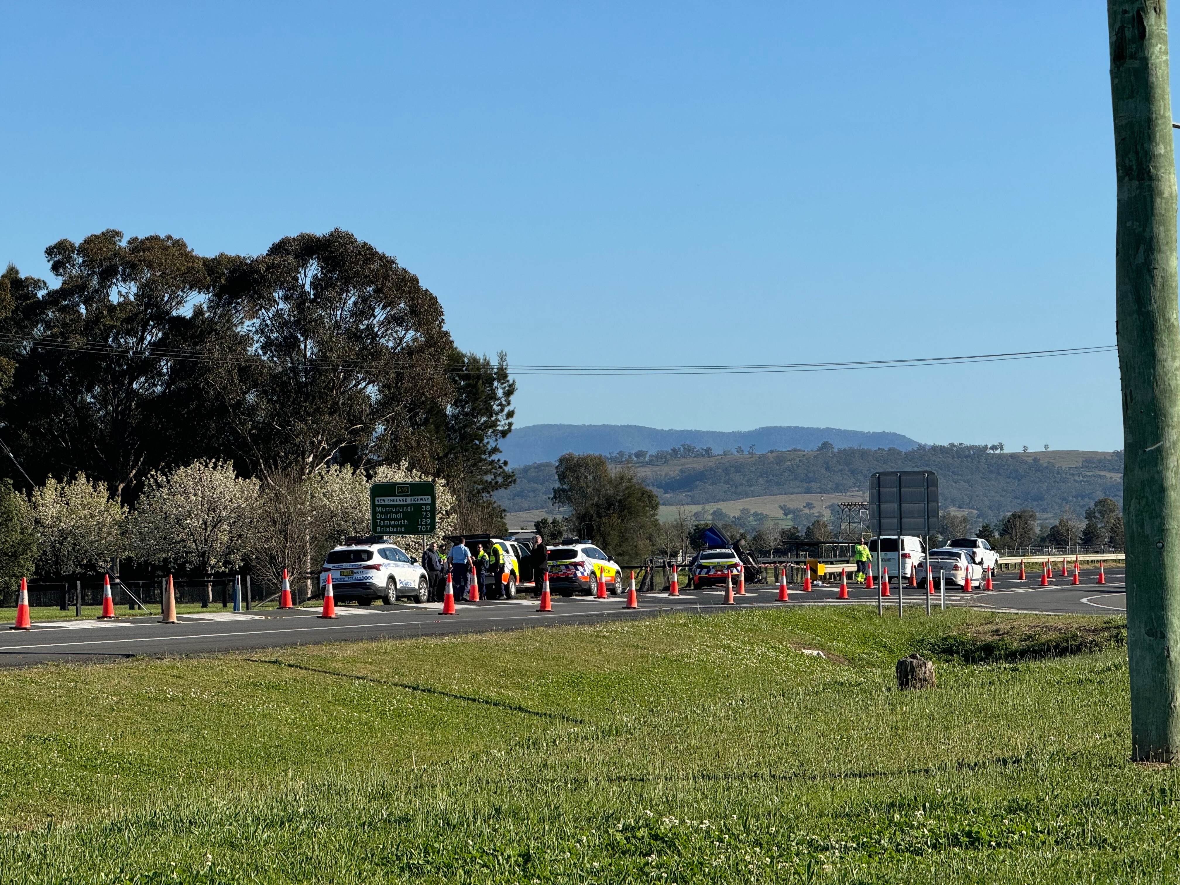 Four police cars on the side of a road at the crash site.