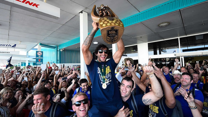 Johnathan Thurston carries the NRL premiership trophy in Townsville