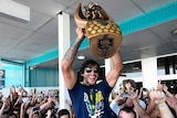 Johnathan Thurston carries the NRL premiership trophy in Townsville