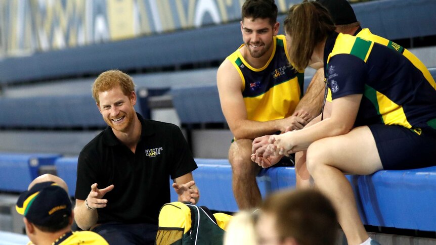 Prince Harry smiles as he talks to a group of six athletes