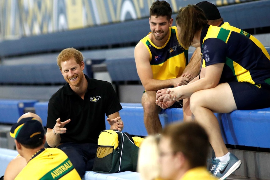 Prince Harry smiles as he talks to a group of six athletes