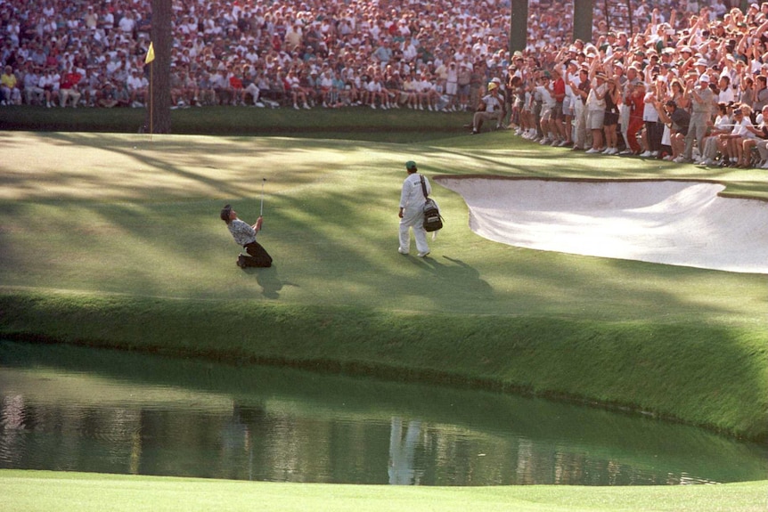 Greg Norman falls to his knees as the gallery looks on at the 15th hole at Augusta National