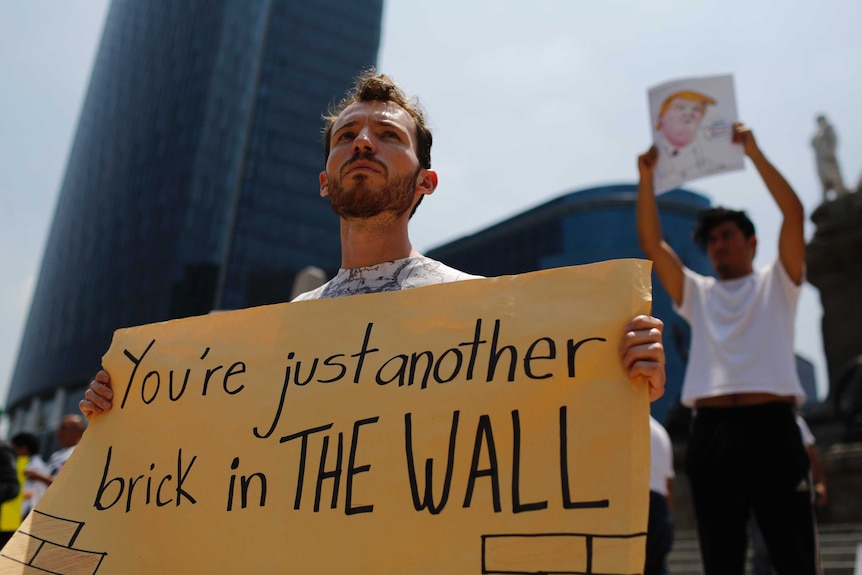 Demonstrators hold placards during a protest against Donald Trump's visit.