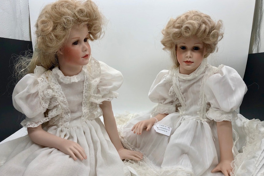 Set of twin porcelain dolls with loosely curled blonde hair, old fashioned clothes