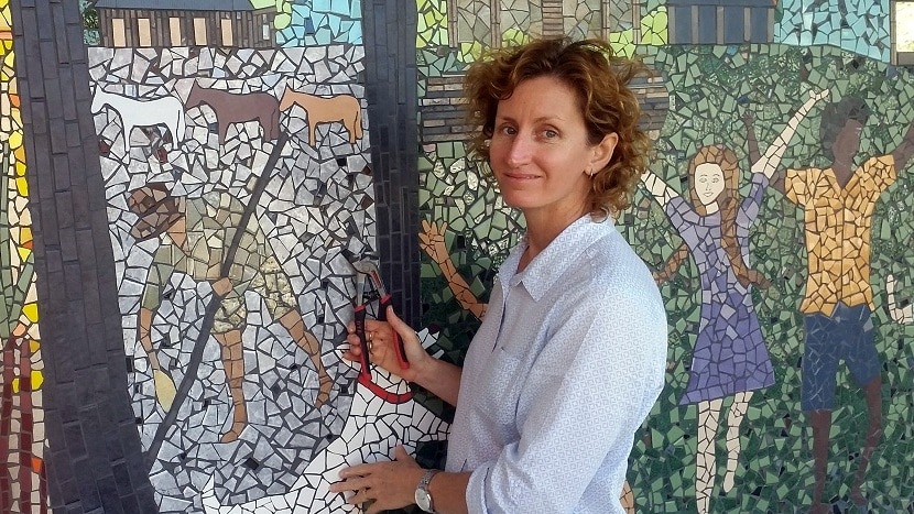 Ingham artist Kate Carr places a tile on the Mercer Lane Mosaic.