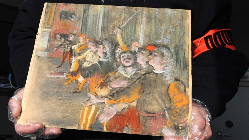 Close view of a small painting showing a line of men singing is held in the gloved hands of an unidentified person