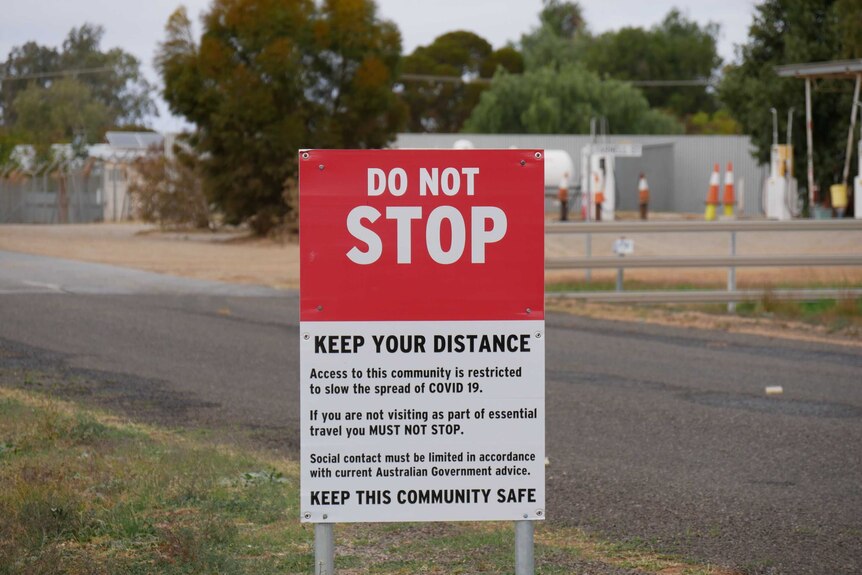 A sign headlined 'DO NOT STOP' and explanatory text, set up next to a road that is visible in the background.