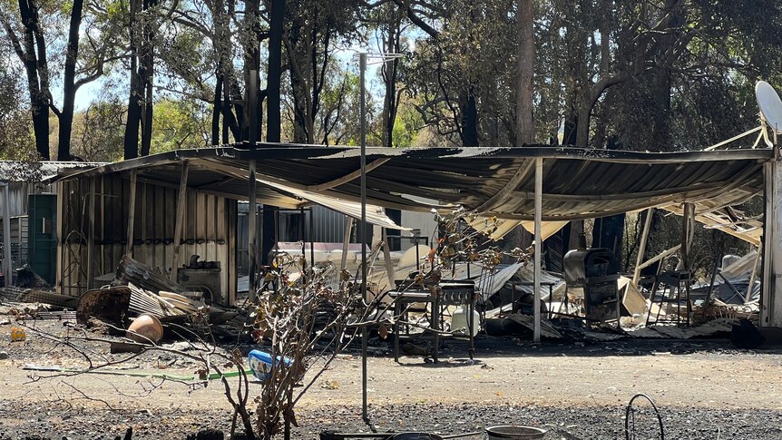 A large burnt out house with trees in the back-ground