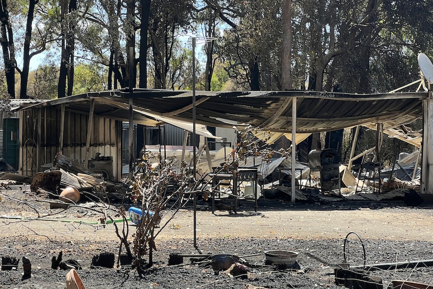 A large burnt out house with trees in the back-ground