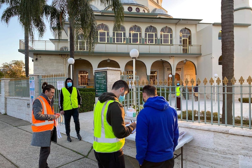 people signing in a contact sheet outside a mosque