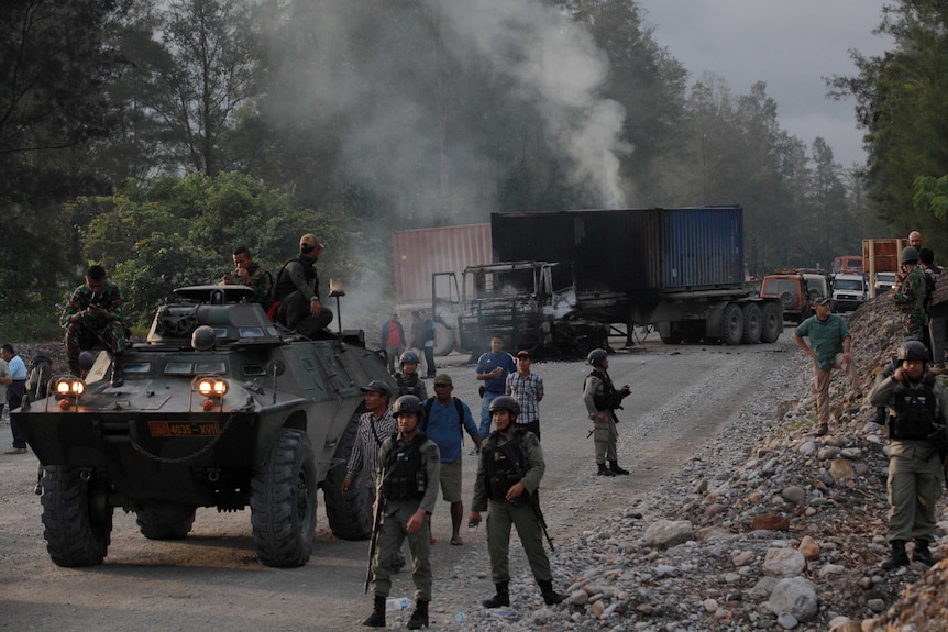 Police and security forces are seen near burning vehicles.