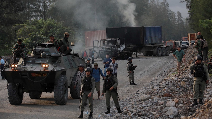 Police and security forces are seen near burning vehicles.