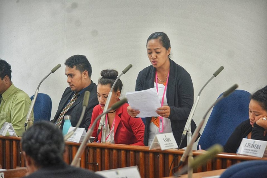 A young woman speaking into a microphone at the Cook Islands Youth Parliament.