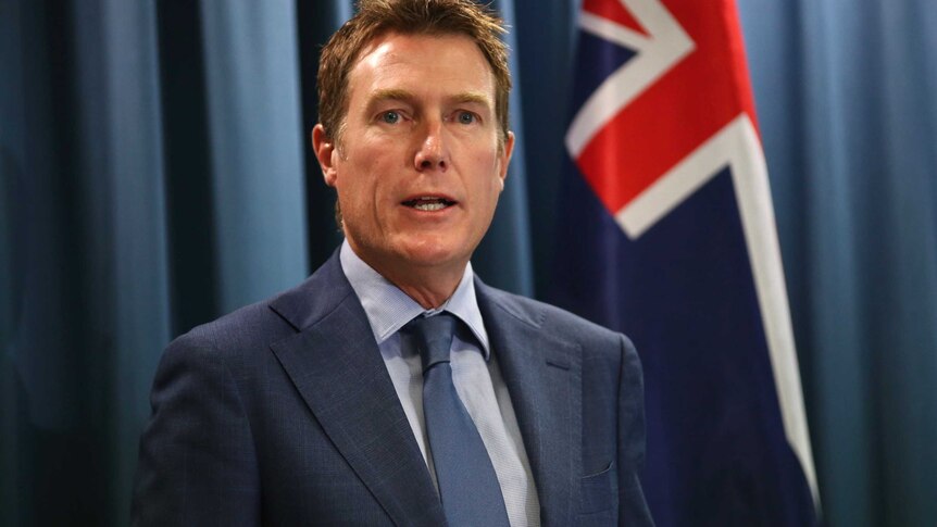 A mid shot of Attorney-General Christian Porter at a media conference with an Australian flag over his left shoulder.