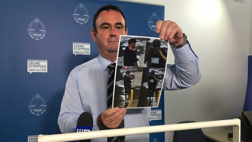 NT Police officer Tony Henrys holds images of a man officers were seeking