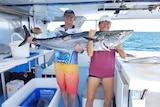 A man and a woman holding a metre-long Spanish mackerel