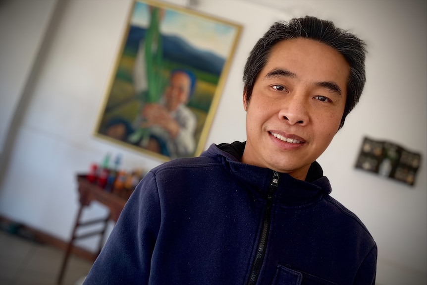 Atom Namkhantee stands in front of a portrait of his mother.